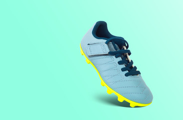 Soccer shoes on a green pastel background. Sport concept. Special sports shoes with soccer cleats. Active leisure, taking care of football comfort.