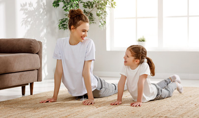 Happy mother and daughter exercising together at home.
