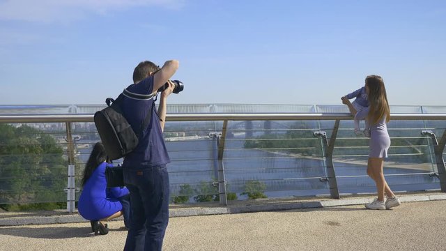 Photographer Shooting Taking Pictures of Mothers with Children. Backstage Photo Session on Pedestrian Bridge on Cityscape Background