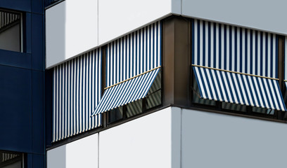 Blue and white stripes Overhang Sunshade Awning on Modern Building Facade Protecting from the Sun. Sun blinds on building facade , awnings.