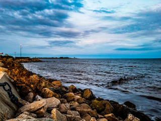 Rocky beach at twilight with waves shoring thereupon.