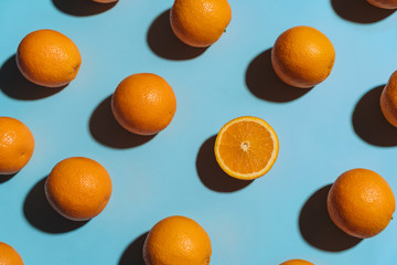 Fruit pattern with oranges on blue paper background. Angled top view. Summer concept
