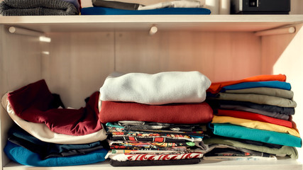 You can choose. Clothes neatly folded on shelves. Stack of colorful clothing