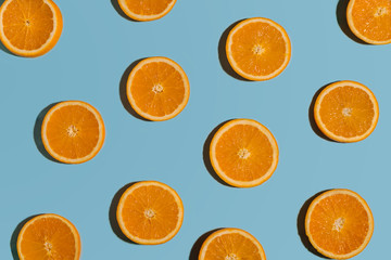 Fruit pattern with sliced oranges on blue paper background. Top view. Summer concept