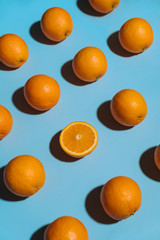 Fruit pattern with oranges on blue paper background. Angled top view. Summer concept