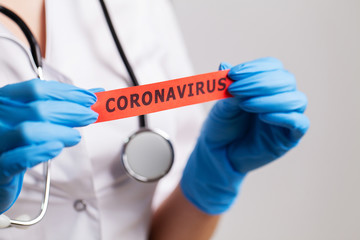 Female doctor in a white coat holding the inscription coronavirus