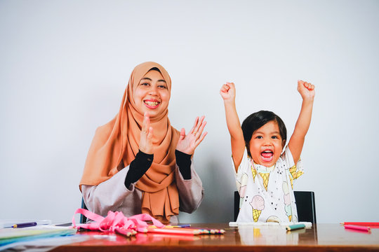 Young musilm woman with her cute daughter playing and learning at home. Motherhood having good time.