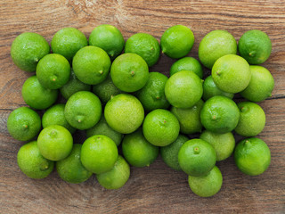 Many green lemons on wooden board