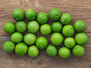 Green lemons on wooden board