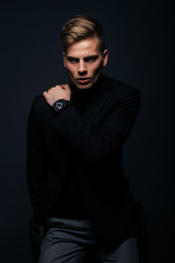 Formally dressed man with sharp jawline in his 20's posing in a studio in front of a black background.