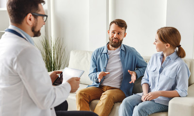 Happy couple talking with doctor in clinic.