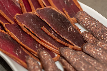 Dried meat beef or meat smoked jerky with spices on a white plate. Traditional Armenian cuisine. Basturma beef jerky. Top view