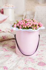 Spray roses in a round box on the bed.