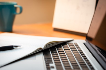 Fototapeta premium Laptop Computer on a Modern Wooden Business Desk with a Notepad and Pen in Unfocused Background.