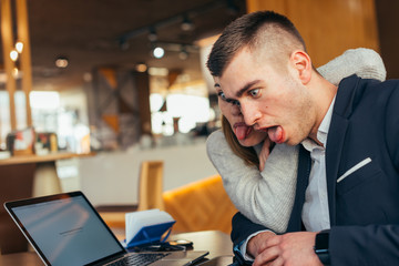 Couple having fun in a cafe ( coffee shop) while making crazy faces and fooling around