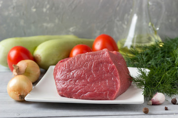 A piece of raw meat and vegetables for cooking.