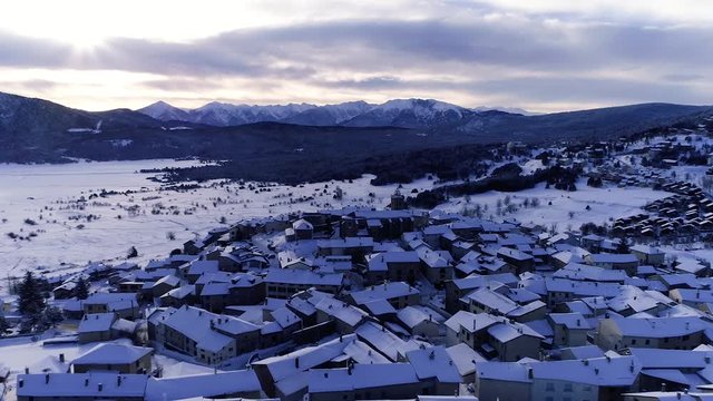 AERIAL DRON ORBIT OF SNOWED ROOF TOPS IN FRENCH VILLAGE, STUNNING PYRENEES VALLEY IN WINTER