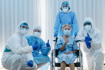 caucasian senior coronavirus covid-19 infected patient sitting on wheel chair with happy doctor and medical team ready to send her back home after treatment and recover from desease at hospital