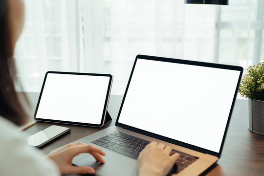 Woman using digital laptop and tablet with smartphone on the table in house. Blank screen for advertising.