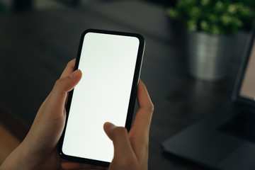 Closeup of young woman hand holding smartphone on the table and the screen is blank, social network concept..