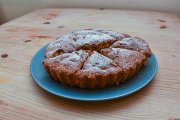 homemade cake with icing sugar on a plate on a wooden table