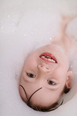 little girl in bath playing with soap foam