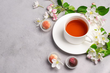 A cup of tea candy truffle made of various chocolate on white om a concrete background. Horizontal frame