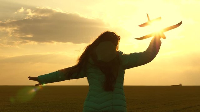 Free girl runs with toy airplane on field in sunset light. healthy children play toy airplane. girl wants to become pilot and an astronaut. teenager dreams of flying and becoming pilot. Slow motion