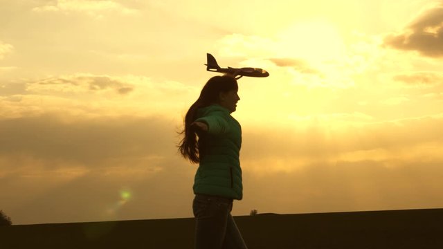 healthy child play toy airplane. teenager dreams of flying and becoming pilot. Slow motion. girl wants to become pilot and an astronaut. Free girl runs with toy airplane on field in sunset light.