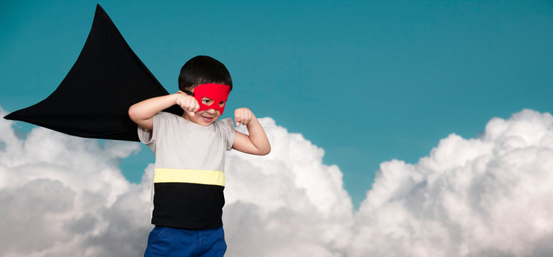 The boy dressed up in a superhero outfit, pretending to fight on the sky background.Study concepts And development of young children.