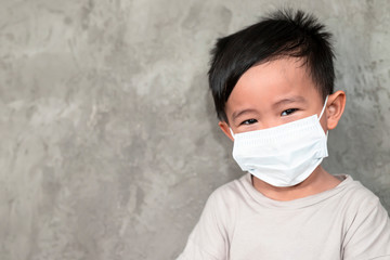 A boy wearing medical face mask for pollution or coronavirus,child itchy eyes and nose, Kid scratching nose while wearing protection mask.Protection against contagious disease, coronavirus.