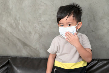 A boy wearing medical face mask for pollution or coronavirus,child itchy eyes and nose, Kid scratching nose while wearing protection mask.Protection against contagious disease, coronavirus.