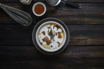 Banana Compote after poured with coconut milk, served on the wooden table.