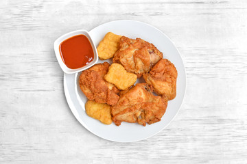 Fried chicken on a white plate set on a white wood table