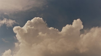 volumetric cumulus cloud lit by the sun on a dim blue sky