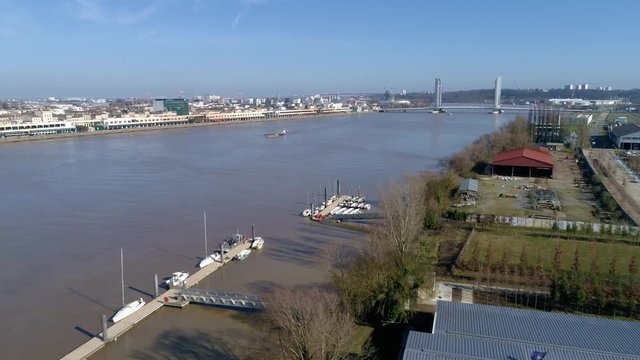 Approaching cargo barge boat in the Garonne river in Bordeaux France with Chaban Delmas Bridge in the distance, Aerial flyover shot