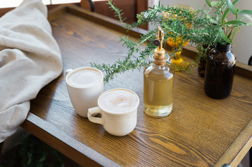two mugs of coffee on wood coffee table with fresh herb plant