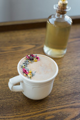 Coffee with dried flowers and herb and flavored syrup behind on wood coffee table