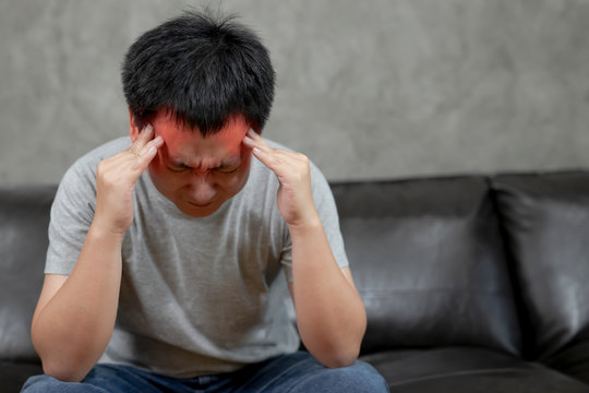 Young man is suffering from a headache,picture showing how much his head hurts,experiencing pain, looking miserable and exhausted,Concept healthcare and medical.