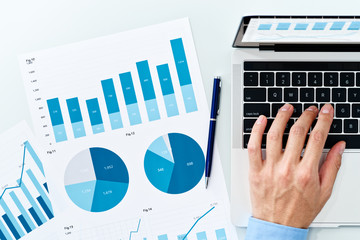 Financial reports and Laptop. Business man preparing reports. Many graphs and charts.
