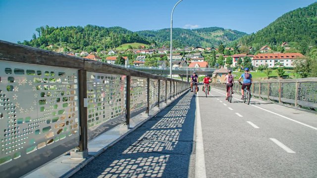 Four of cyclists cheering each other while cycling on bridge, Slovenia