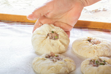 Female hands lay homemade patties from raw dough with meat filling on a kitchen towel. Close-up