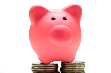 Pink piggy Bank on a white background stands on coins, front view. The concept of savings, financial management.