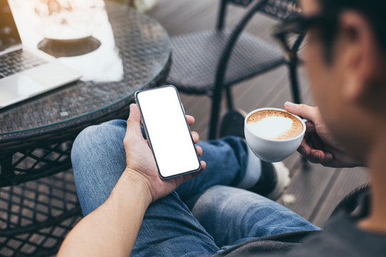cell phone Mockup image blank white screen.man hand holding texting using mobile on desk at coffee shop.background empty space for advertise.work people contact marketing business,technology