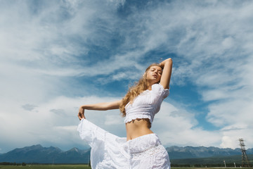 Girl in a white dress on a background of mountains and a cloudy sky