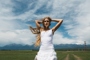 Obraz premium Girl in a white dress on a background of mountains and a cloudy sky