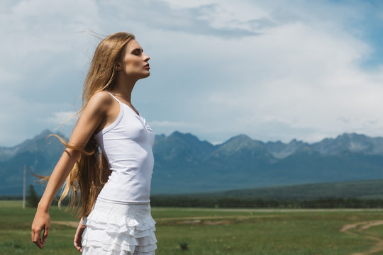 Girl in a white dress on a background of mountains and a cloudy sky