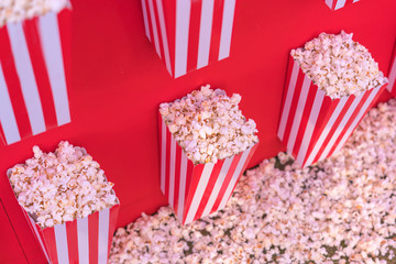 salted popcorn in a paper bucket on red background