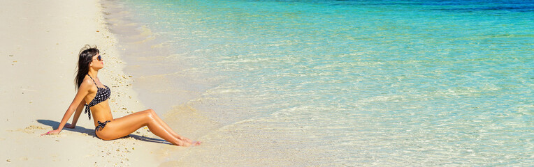 Young woman in black swimwear enjoying  sunny day on the beach.  Banner edition.