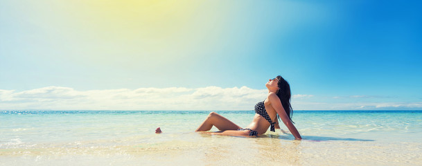 Girl in black swimwear tan on  beautiful beach. Tropical vacation concept. Banner edition.